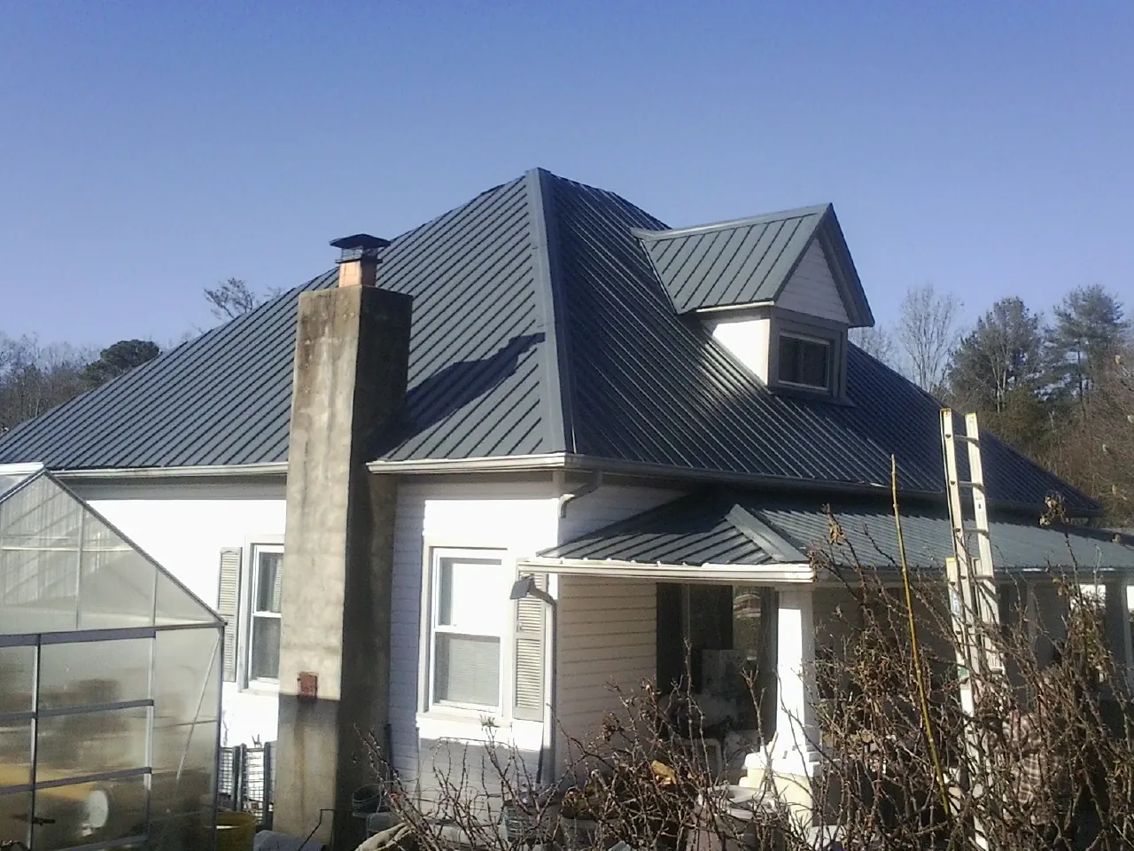 Dark blue standing seam metal roof on a white farmhouse with dormer — Slate & Tile Roof Repair by Roofing Brothers in South Sutton