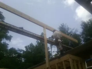 Carpenter setting a ridge beam over a new addition frame — Ice Dam Removal by Roofing Brothers in South Sutton