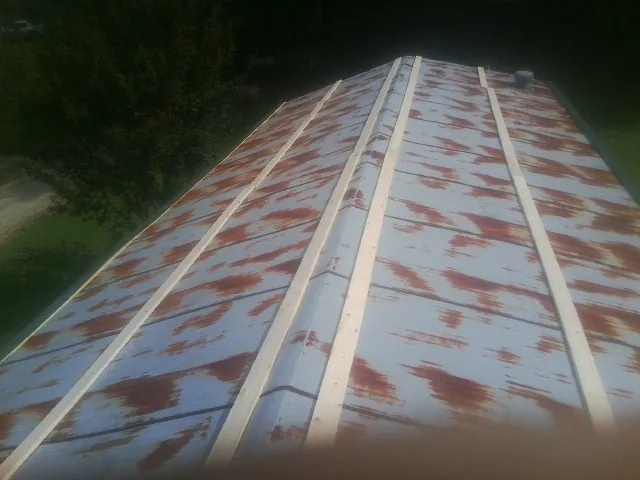 Rusted metal roof panels with new wood purlins before replacement — Storm Damage Roof Repair in South Sutton by Roofing Brothers
