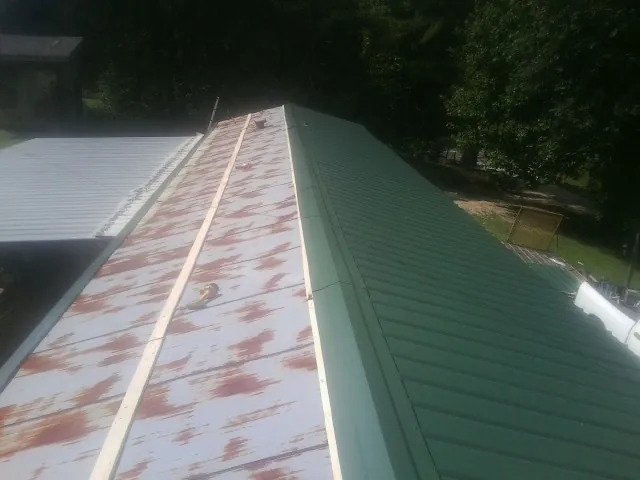 Old rusted panels beside newly installed green metal roofing — Wind Damage Roof Repair by Roofing Brothers in South Sutton