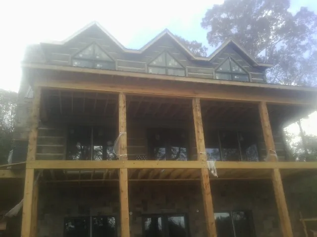 Dormers and porch framing on a large log home under construction — Roof Coating work by our crew in South Sutton