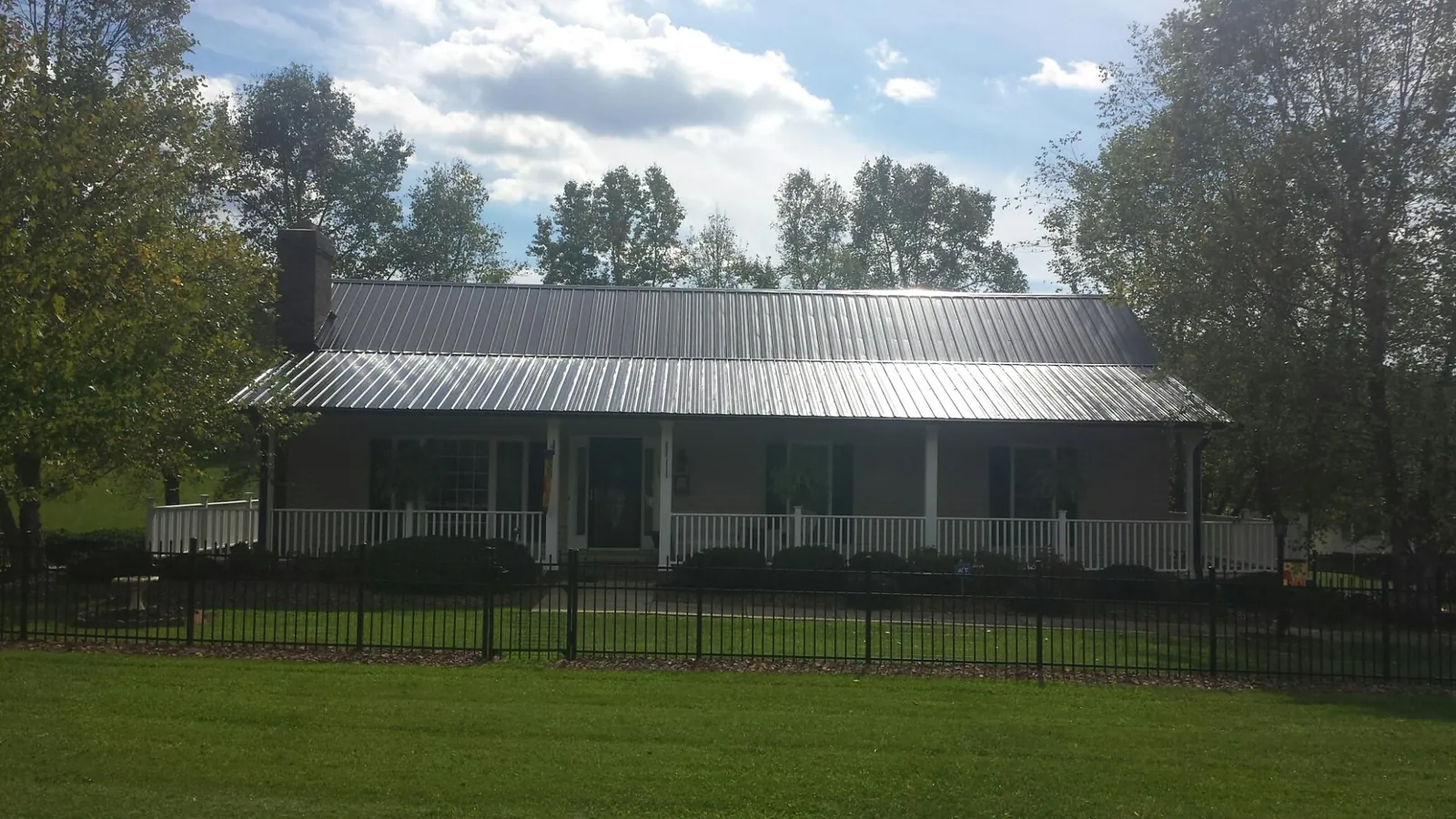 Gray metal roof on a brick ranch with a full width front porch — Gutter Guard Installation work by our crew in South Sutton